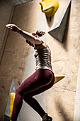Young woman jumping off climbing wall