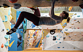 Young woman rock climbing upside-down