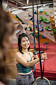 Smiling woman exercising at gymnastics rings in climbing gym
