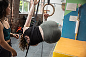 Woman hanging from gymnastics rings in gym
