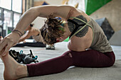 Young female rock climber stretching in climbing gYm