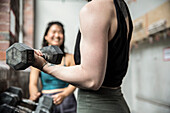 Close up woman working out with dumbbell in gym