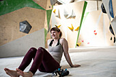 Smiling young female rock climber resting in climbing gym