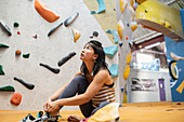 Female rock climber looking up at climbing wall in gym