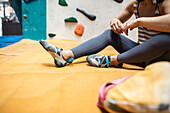 Female rock climber resting on mat in climbing gym