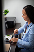 Businesswoman raking zen garden at office desk