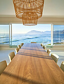 Rattan lights over wooden dining table with ocean view