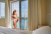 Happy couple hugging on hotel balcony with sunny ocean view