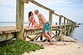 Affectionate boyfriend and girlfriend on wooden beach pier