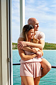 Happy couple hugging on sunny houseboat patio