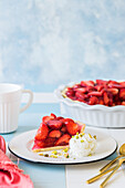 Strawberry jelly pie with a scoop of vanilla ice-cream and pistachios on tile background
