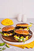 Burger mit Rindfleisch in dunkler Sauce, Rucola, Mango, Avocado und Knoblauch-Joghurt-Dip