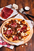 Pizza with caramelised onions, mushrooms, blue cheese and prosciutto