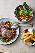 Leg of lamb in herb marinade with vegetables, chips and salad