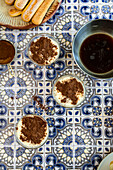 Tiramisu served as individual servings in glasses on a tiled surface with ingredients