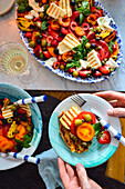 Tomato salad with grilled halloumi, fruits, and olives on toasted bread