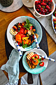 Tomato salad with grilled halloumi, fruits and olives on toasted bread