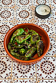 Roasted Padron peppers on a tiled background