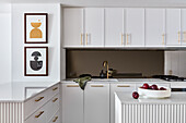 Wohnküche mit geriffelten Tischlerarbeiten, Armaturen aus gebürstetem Gold und Arbeitsplatten aus Marmor