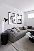 A modern monochromatic living room with a grey corner sofa, abstract artwork and marble coffee table