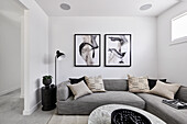 A modern monochromatic living room with a grey corner sofa, abstract artwork and marble coffee table