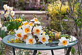 Blumenstrauß aus Narzissen (Narcisssus) und Forsythie (Forsythia) auf Gartentisch liegend