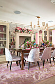 Dining room with lush floral decoration, set table, and velvet chairs