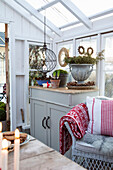 Cozy rattan armchair and chest of drawers with plants in the greenhouse