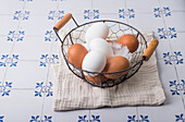 Fresh brown and white eggs with feathers in a basket
