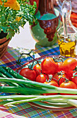 Frühlingszwiebeln, Tomaten und Olivenöl auf Tisch in der Sonne