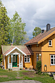 Gelb gestrichenes Holzhaus in ländlicher Umgebung