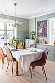 Festive dining table in a room with green painted wood paneling and wallpaper