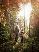 Mother and daughter foraging mushrooms in the forest