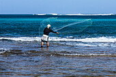 Fisherman casting his net in the surf on Haena Beach, Hawaii