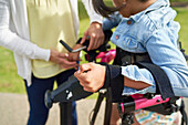 Mother helping disabled daughter with arm straps on rollator