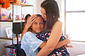 Mother hugging disabled daughter at home
