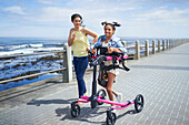 Mum and disabled daughter with rollator jogging at the beach