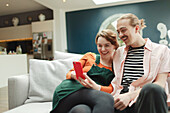 Happy couple with smart phone on living room sofa