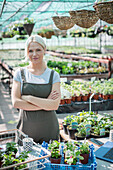 Female garden shop owner working in greenhouse