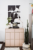 Black and white poster above pink sideboard