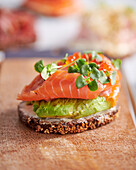 Open faced sandwich on sourdough rye bread with smoked salmon and sliced avocado