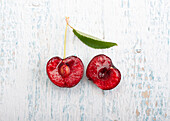 Halved cherry with stem and leaf on a wooden background