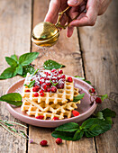 Waffles with wild strawberries, red currants and icing sugar