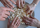 Schüssel Popcorn und viele Hände