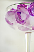 Glass with purple hydrangea flower ice cubes