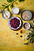 Overhead of ingredients for making raspberry dessert with whipped cream, honey and oats (cranachan)