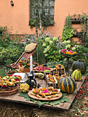 Gedeckter Tisch mit Häppchen für eine Kürbisparty im Garten