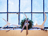 White antlers, cones and fir wreath in front of an old barn window