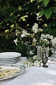 Festively laid table with white tablecloth and spiraea