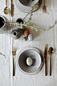 Set Easter table with ceramic tableware and naturally coloured Easter eggs